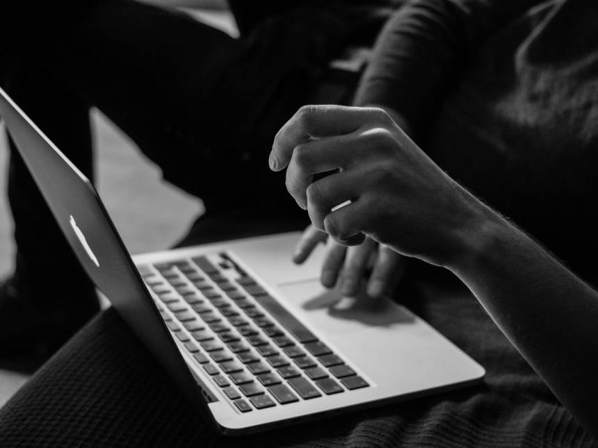 grayscale photo of person using MacBook